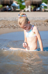 Little girl playing on the beach by the sea