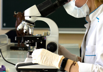 A female doctor conducts medical research using a microscope.