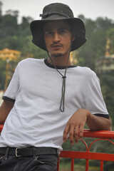 A north Indian young guy posing outdoor with wearing boonie hat and white tshirt and looking at...