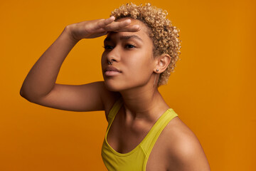 Body language concept. Mixed-race blondie looking far in distance covering eyes from sun with palm...