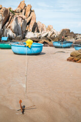 A round fishing boat stands with an anchor on the picturesque beach with large rocks. The beauty of unspoiled nature. Amazing places in the world.