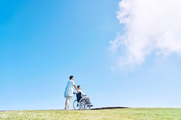 介護士と車椅子に乗る高齢者　屋外