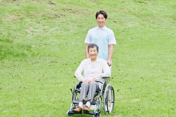 Obraz premium 介護士と車椅子に乗る高齢者 屋外