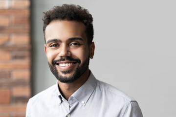 Fototapeta premium Young businessman closeup portrait, mixed race latin confident man smiling and looking to camera in modern office.