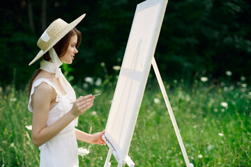Woman in white dress in nature paints a picture of a landscape hobby
