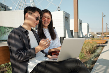 Young confident businesswoman making presentation of points of new project to colleague at working meeting in urban environment