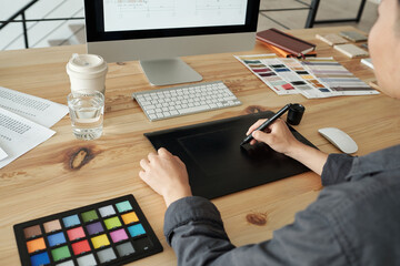 Hands of young female designer with stylus pen and graphic tablet drawing sketch on computer screen...