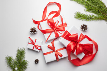 Christmas gift boxes with red ribbon and green pine tree branch with cones on white