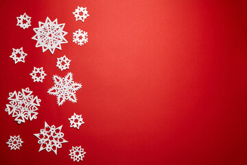 Fototapeta na wymiar Christmas decoration with white paper snowflakes on red