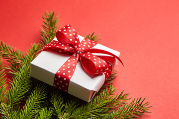Fototapeta na wymiar Gift box with green Christmas tree branch on red