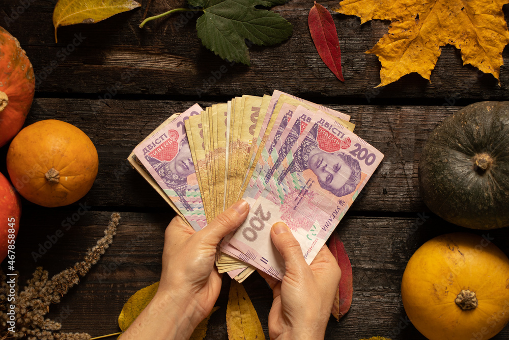 Wall mural female hands hold banknotes in denominations of one hundred and two hundred hryvnia on a wooden tabl