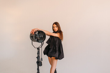 young beautiful girl, model appearance in a black dress, high boots on her legs, in the studio on a white background
