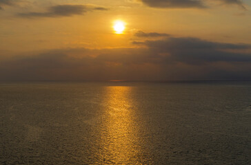 The sun in the clouds over the sea horizon.
