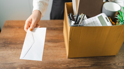 Business woman sending resignation letter and packing Stuff Resign Depress or carrying business cardboard box by desk in office. Change of job or fired from company