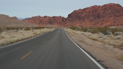 Fototapeta na wymiar Road trip, driving auto in Valley of Fire, Las Vegas, Nevada, USA. Hitchhiking traveling in America, highway journey. Red alien rock formation, Mojave desert wilderness looks like Mars. View from car.