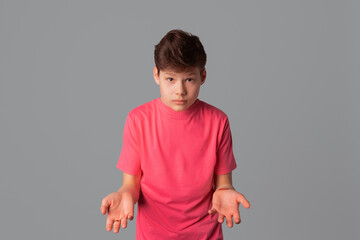 Portrait of puzzled handsome teenager boy, having doubtful confused uncertain facial expression, standing over gray background