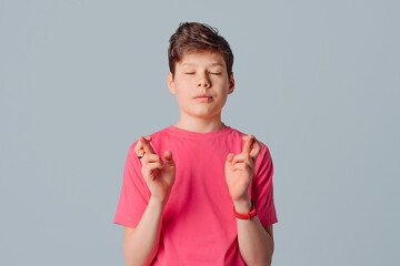 Hopeful handsome teenager boy cross fingers make wish, desperate superstitious guy make gesture...