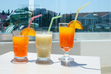 Delicious freshly made cocktails with straws and orange slices on the balcony in front of the hotel.