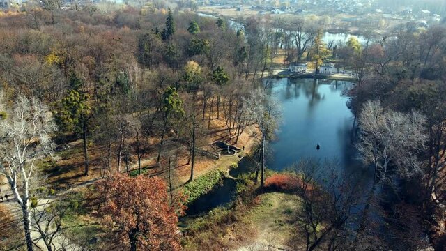 Arial drone view flight over lake in park on sunny autumn day