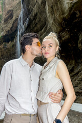 A guy and a girl are kissing romantically in the mountains of the Kabardino-Balkarian Republic in Russia against the backdrop of the Chegem gorge with its famous waterfalls and the river called Chegem
