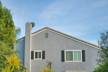 Side exterior of a house with gray siding and trees outdoors at California