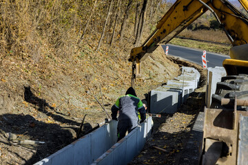 Construction workers installing precast u-shape concrete drain at the reconstruction road