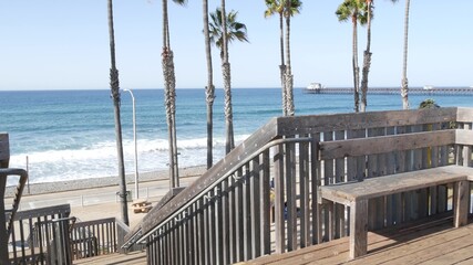 Wooden stairs, beach access in Oceanside, California USA. Coastal stairway, pacific ocean waves and palm trees. Vacations by sea in United States. Sunny tropical day, summertime aesthetic. Staircase.