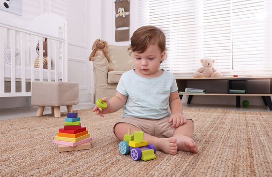 Cute little boy playing with toys on floor indoors