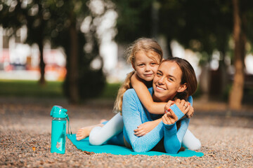 Cute girl embracing mother on exercise mat
