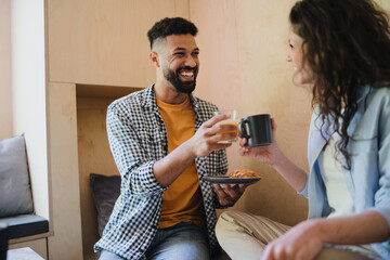 Happy couple sitting, resting and drinking coffee indoors in a tree house, weekend away.