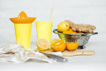 Juice of orange and lemon. A wooden board with oranges on a white table. Freshly squeezed orange juice. Lemon, orange, ginger.