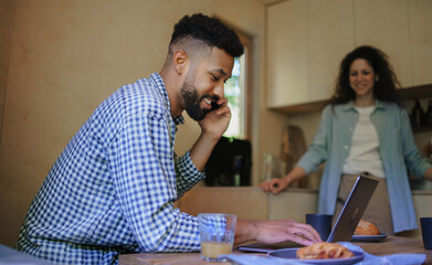 Fototapeta premium Happy couple with laptop sitting and resting indoors in tree house, weekend away and remote office.
