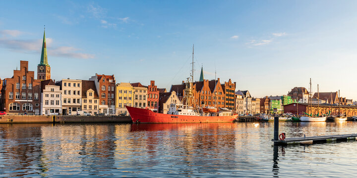 Germany, Schleswig-Holstein, Lubeck, Panoramic view of river Trave with moored ship and historic townhouses in background
