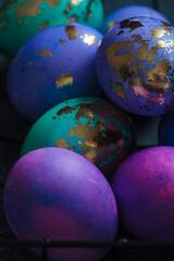 Easter eggs purple and blue with golds on dark background.