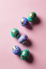 Easter eggs purple and blue with golds on pink background.