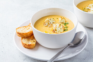 Vegetarian cream cheese soup with cauliflower in white bowl. Healthy vegan food concept.