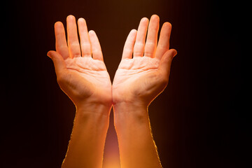 Open palms as metaphor for Christian religion. Human hands with bright glow. Concept of faith in god and religious rituals. Gesture of prayer and religious worship. Mercy gesture on dark background