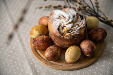 Craft easter cake sprinkled with powdered sugar and Easter eggs on a wooden board