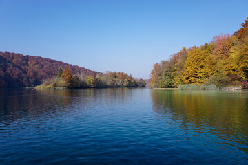 calm blue lake with reflections of hills and forest in intense fall colors
