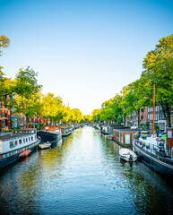 Schöner Sonnenuntergang über Amsterdam Stadt Landschaft in Niederlande mit Blumen und Fluss an der Brücke im Sommer. Natur Haus Boot Architektur Gracht