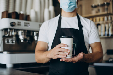 Male barista holding coffee in cardboard cup