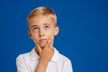 White blonde boy holding his chin while looking upward