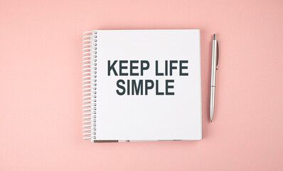 KEEP LIFE SIMPLE text on notebook with pen on the pink background