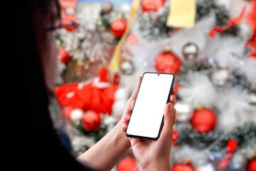 Girl with a phone front of a Christmas tree. Isolated phone display for app or greeting text promotion