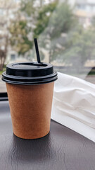 A paper coffee cup on the dashboard of the car and blurry green background