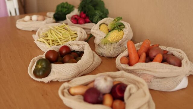 Vegetables in reusable eco cotton bags on wooden table. Zero waste shopping concept. Canvas grocery bag with tomatoes, carrot, potato. Plastic free items