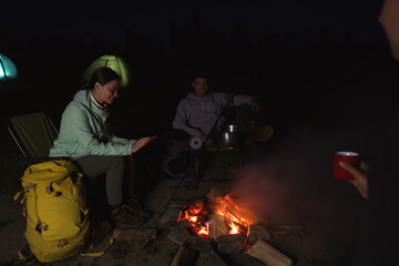 Obraz premium People sitting near bonfire in camp at night