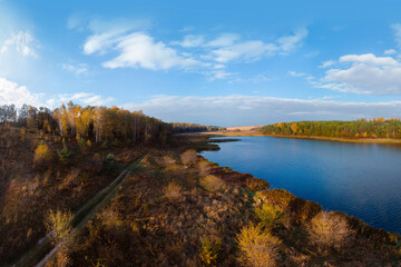 Aerial wide view of lake at sunrise in autumn. Meadows, orange grass, trees. Colorful landscape of river sunset. Horodok Ukraine