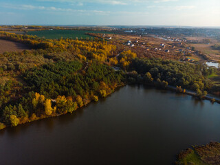 Fototapeta na wymiar Aerial view of sunrise in autumn. top down. Meadows, orange grass, trees at dawn. Colorful landscape of river coast at sunset in fall. Plowed fields, harvested crops, dry corn. Horodok Ukraine