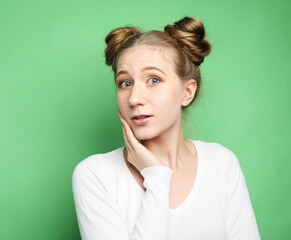 Young surprised woman wearing white shirt over green background